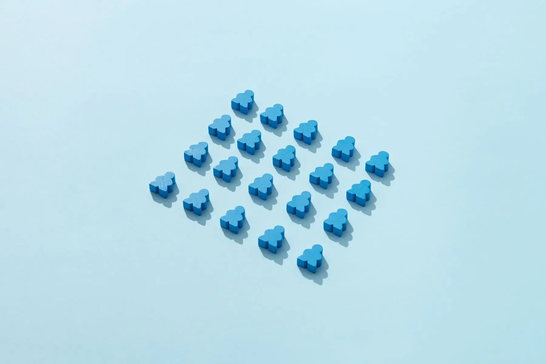 Veinte figuras de madera azules ordenadas en una cuadrícula sobre fondo celeste