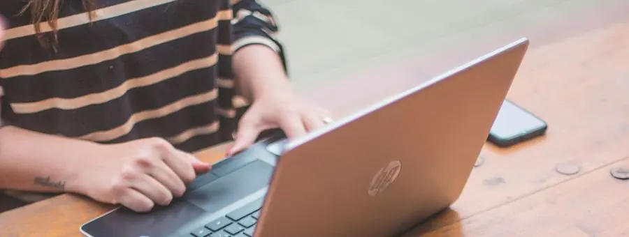 Manos trabajando en un notebook sobre una mesa de madera
